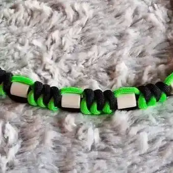 détails du tressage et des perles du collier pour chien anti tiques en paracorde avec des perles céramique EM, coloris vert et noir